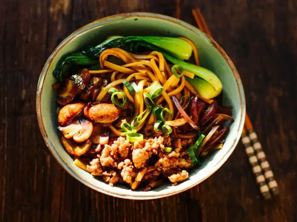 Schüssel mit Yaki Udon Nudeln, Hackfleisch, Pilzen, Pak Choi und Frühlingszwiebeln.